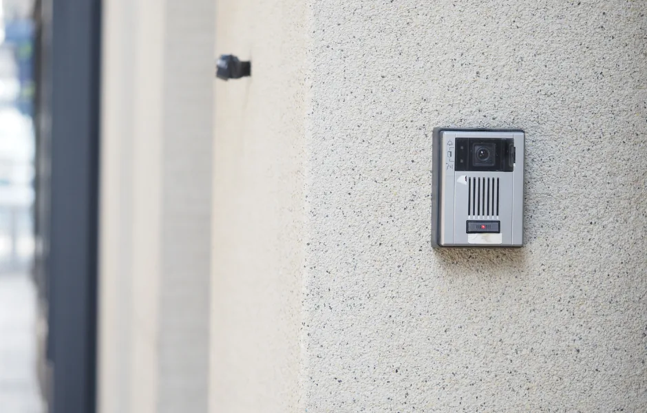 Woman pressing a video intercom buzzer to request entry at an NYC apartment building